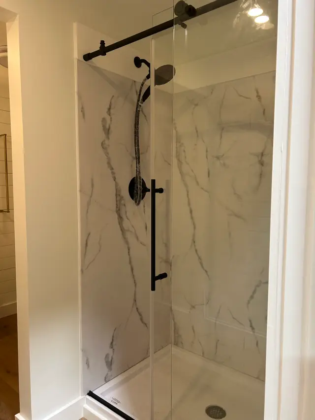 Marble-look walk-in shower with a sliding glass door