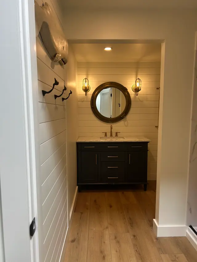 Bathroom vanity with a round porthole mirror and white shiplap walls